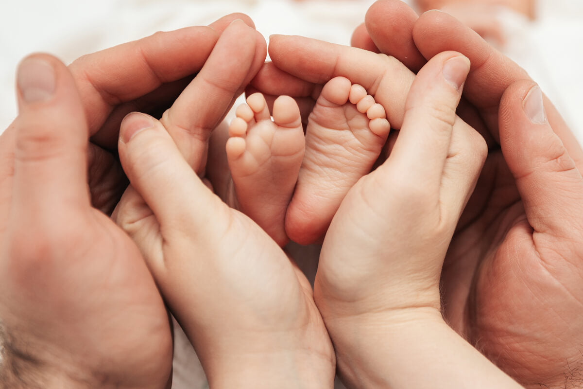 A tender close-up of infant feet embraced by loving hands — perfect for new dads on Father’s Day.