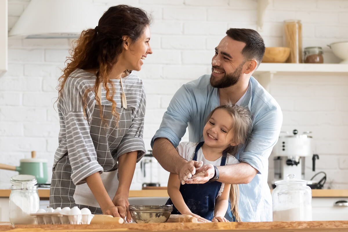 Happy family smiling and baking together in the kitchen on Father’s Day.
