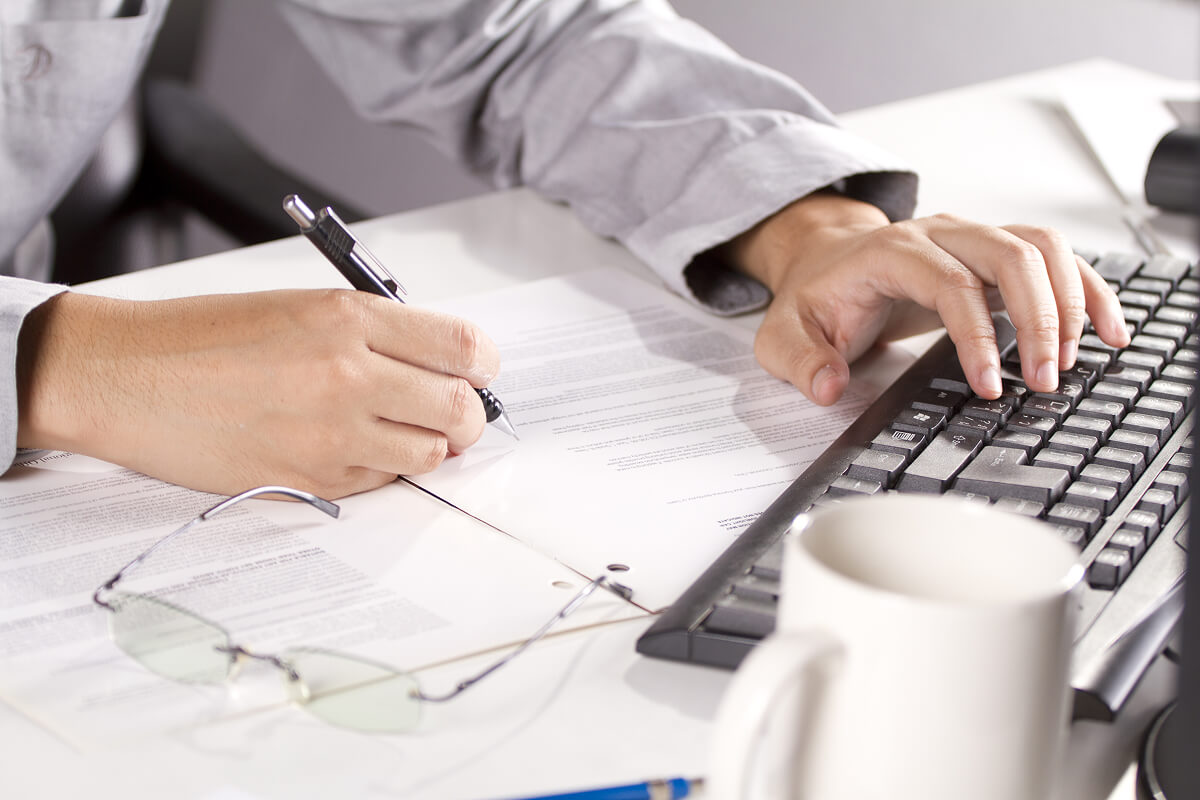 Holiday gift ideas for coworkers including jerky kits, barware sets, and snackable ammo cans on a rustic holiday office desk.