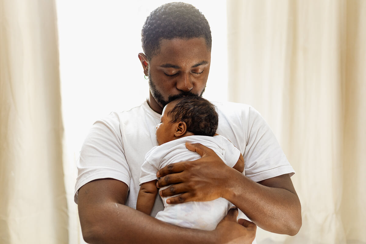 New dad holding newborn baby in a tender moment—perfect for a blog about bold, funny, and flavorful gift baskets for first-time fathers.