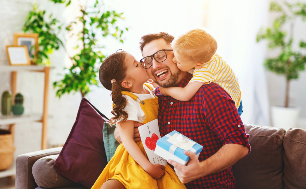 Father with his two kids hugging after a gift exchange on fathers day