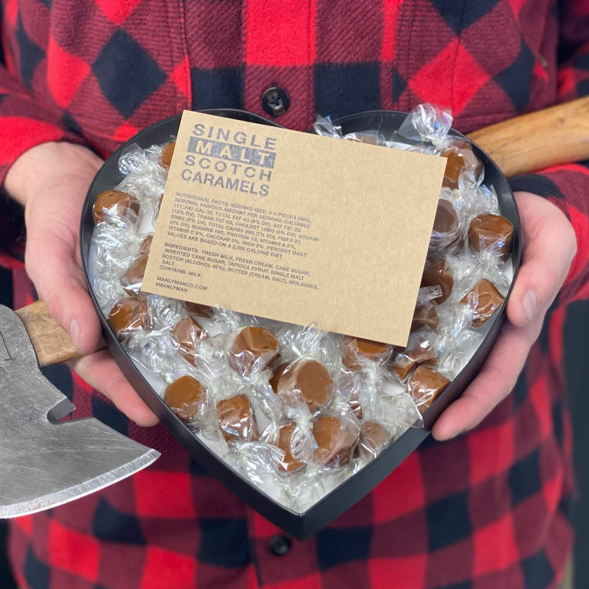 New heart-shaped gift box, filled with single malt scotch caramels, being held by man in flannel shirt