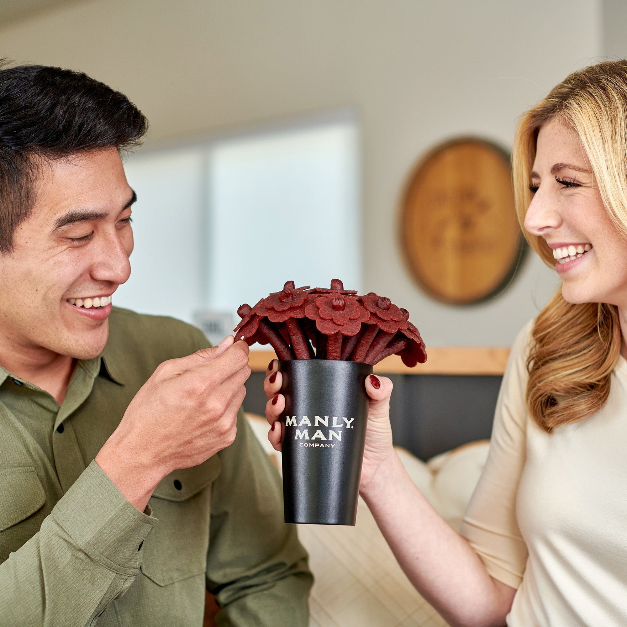 Cute wedded couple exchanging a unique and amazing gift for man. Beef jerky gifts for men in the shape of flowers.