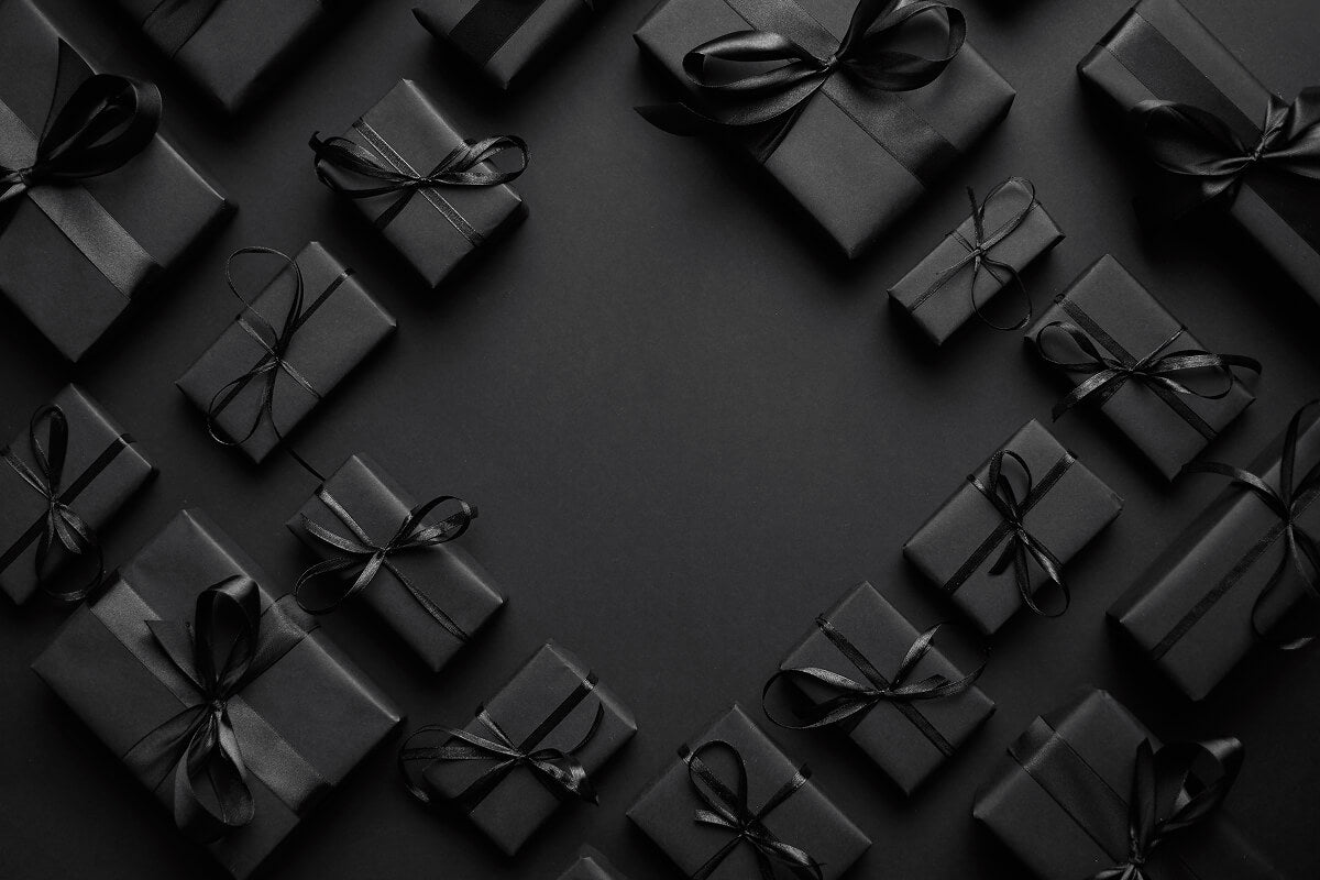 Flat lay of sleek black gift boxes tied with black ribbons, arranged on a dark background—stylish and bold, perfect for aviation-themed gift inspiration.
