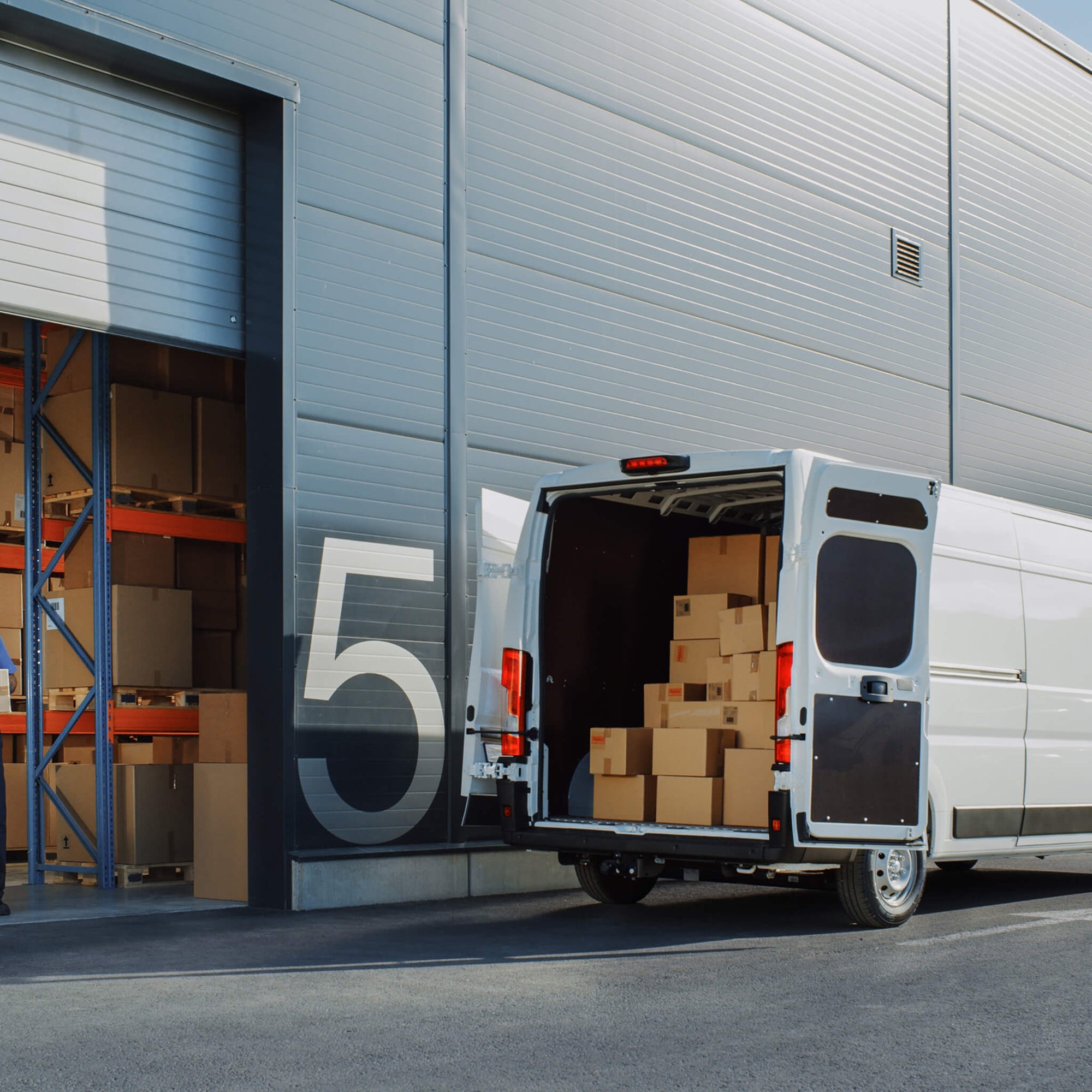 Open delivery van filled with packages parked outside a loading dock—perfect representation of hardworking delivery drivers on the job.