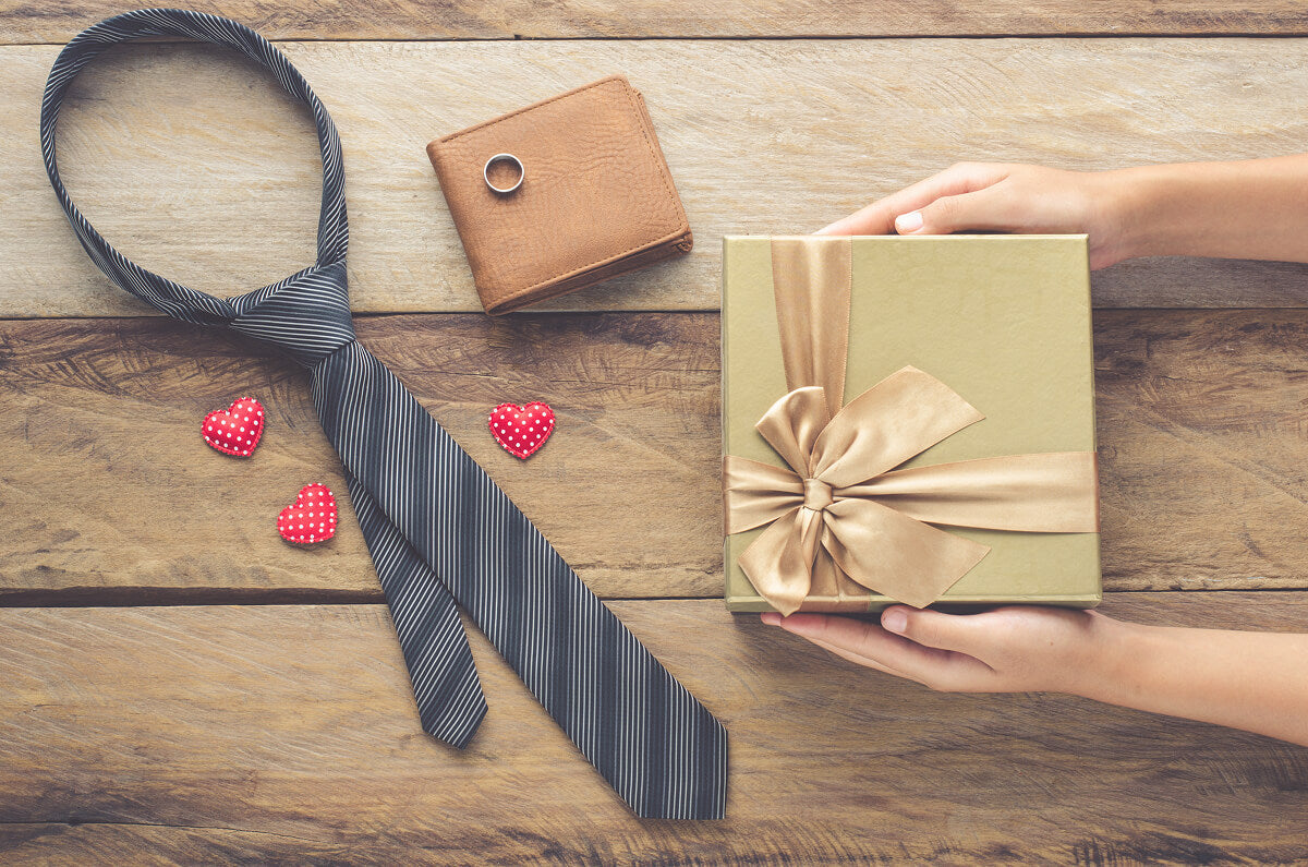 Creative Christmas present ideas for men with jerky bouquets, ammo cans, and festive gift boxes arranged under a tree.