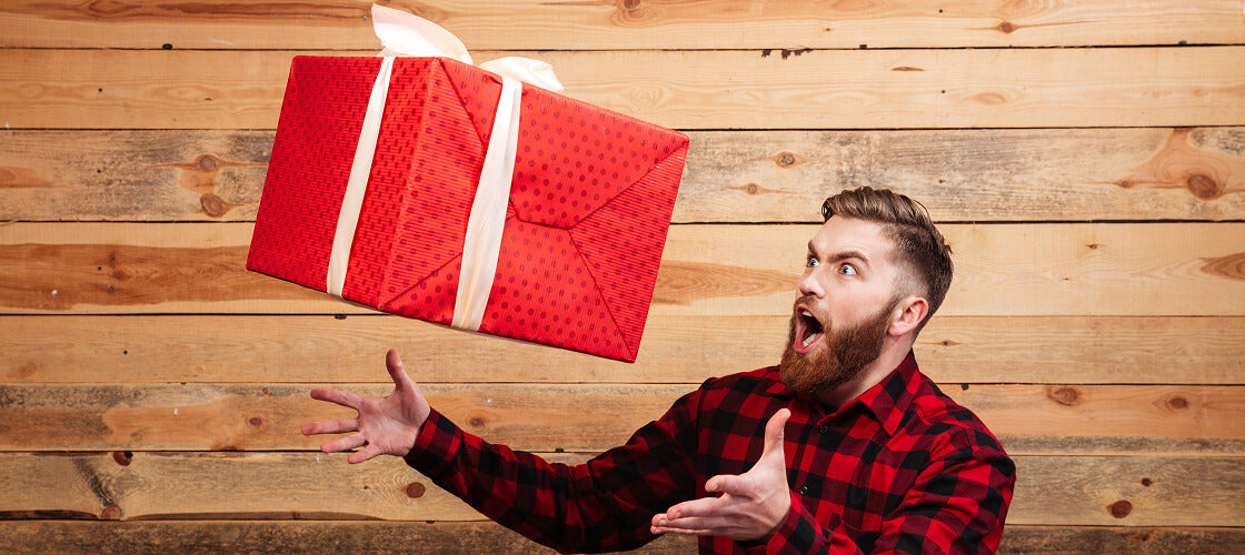Cool Christmas gifts for men featuring jerky bouquets, bacon gift boxes, and rugged snack sets on a holiday-themed table.