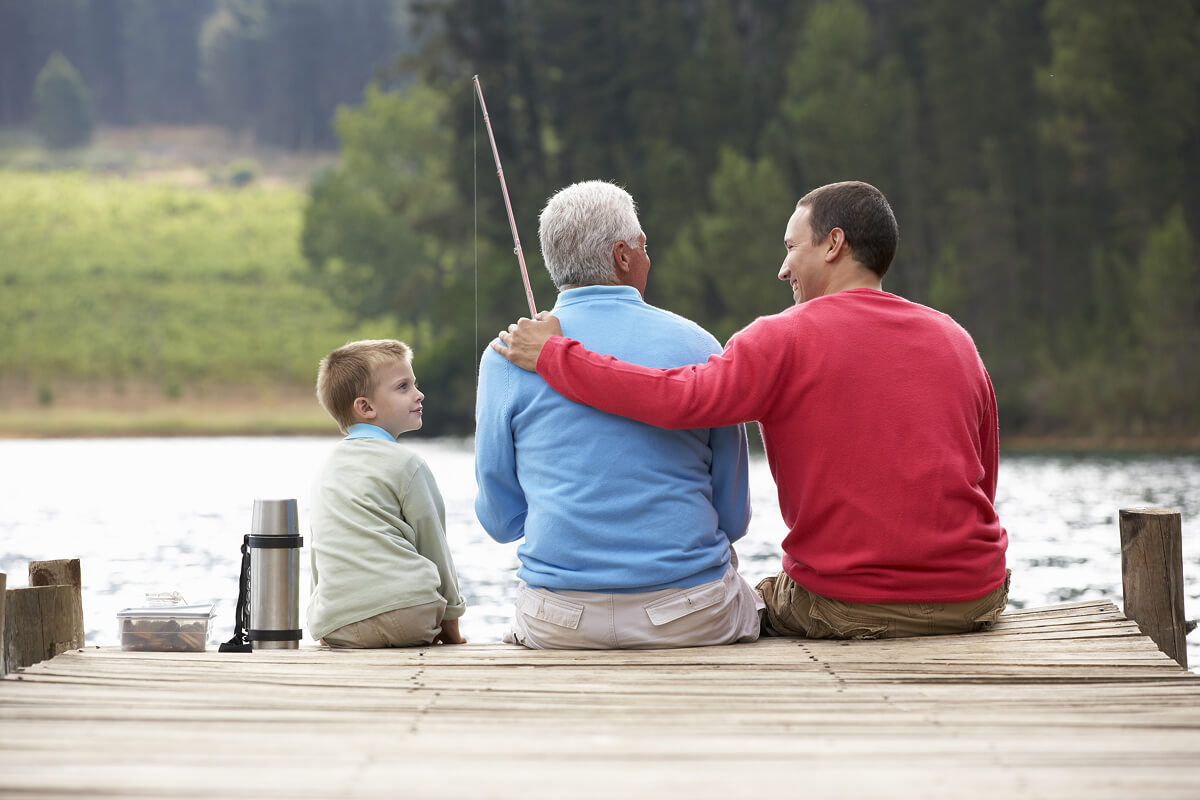 Dad and son sitting on a dock with fishing poles, sharing quality time together for a heartfelt 50th birthday celebration.