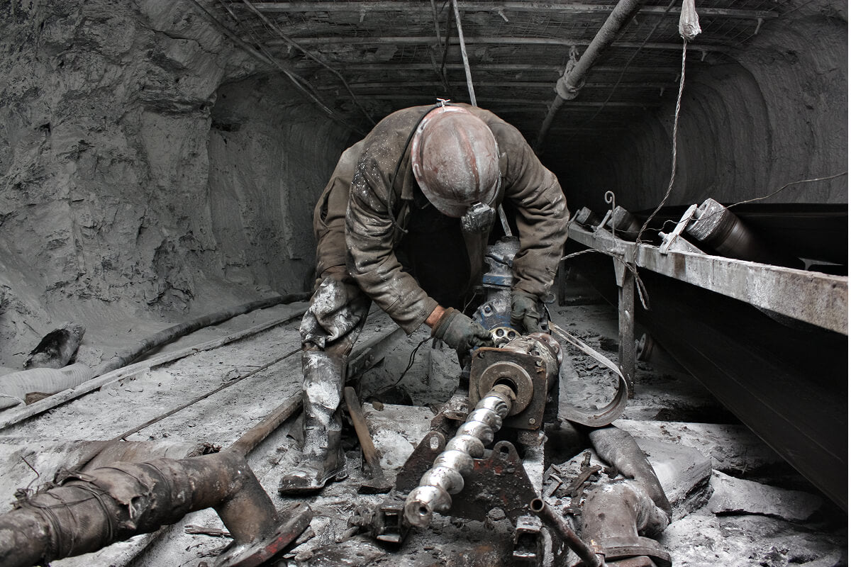 Lineman crouched over heavy cables, performing tough fieldwork.