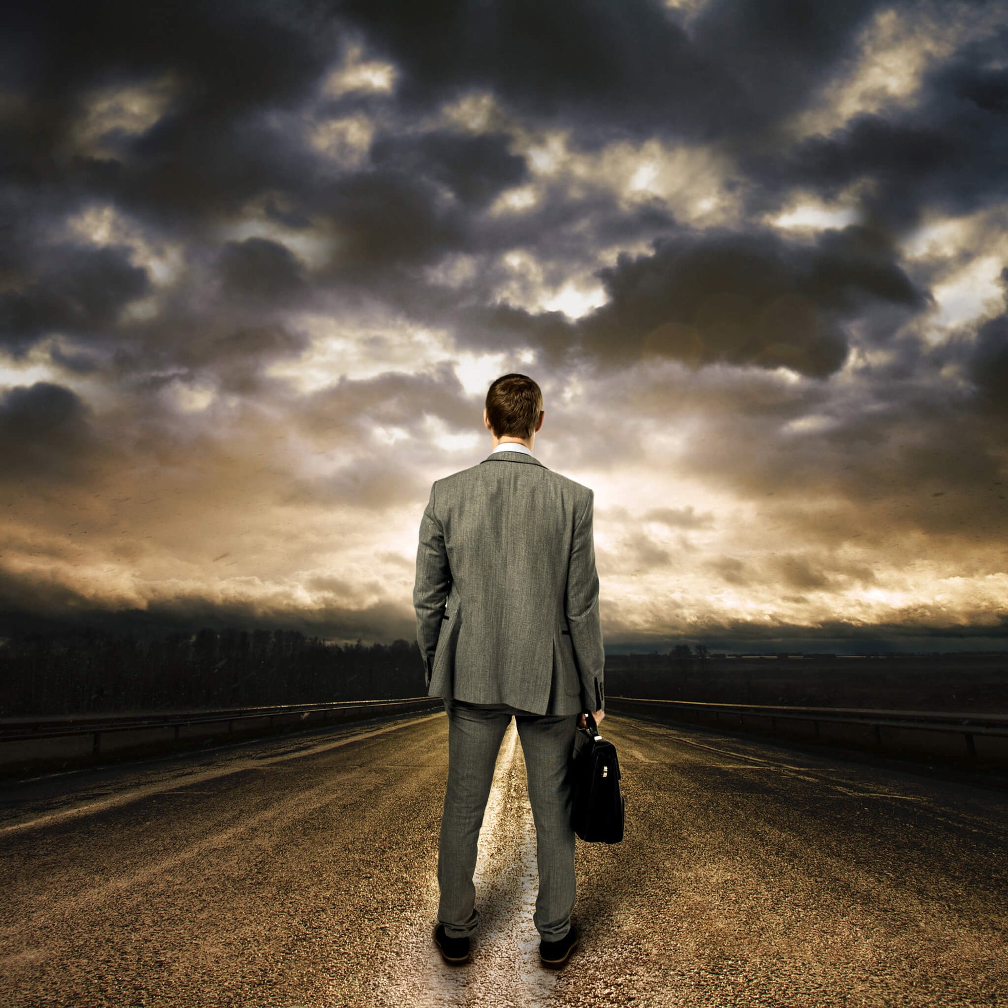 Lone figure on an open road under heavy skies, representing the serious work of FBI agents and the Bloody Mary Kit designed to help them recharge.