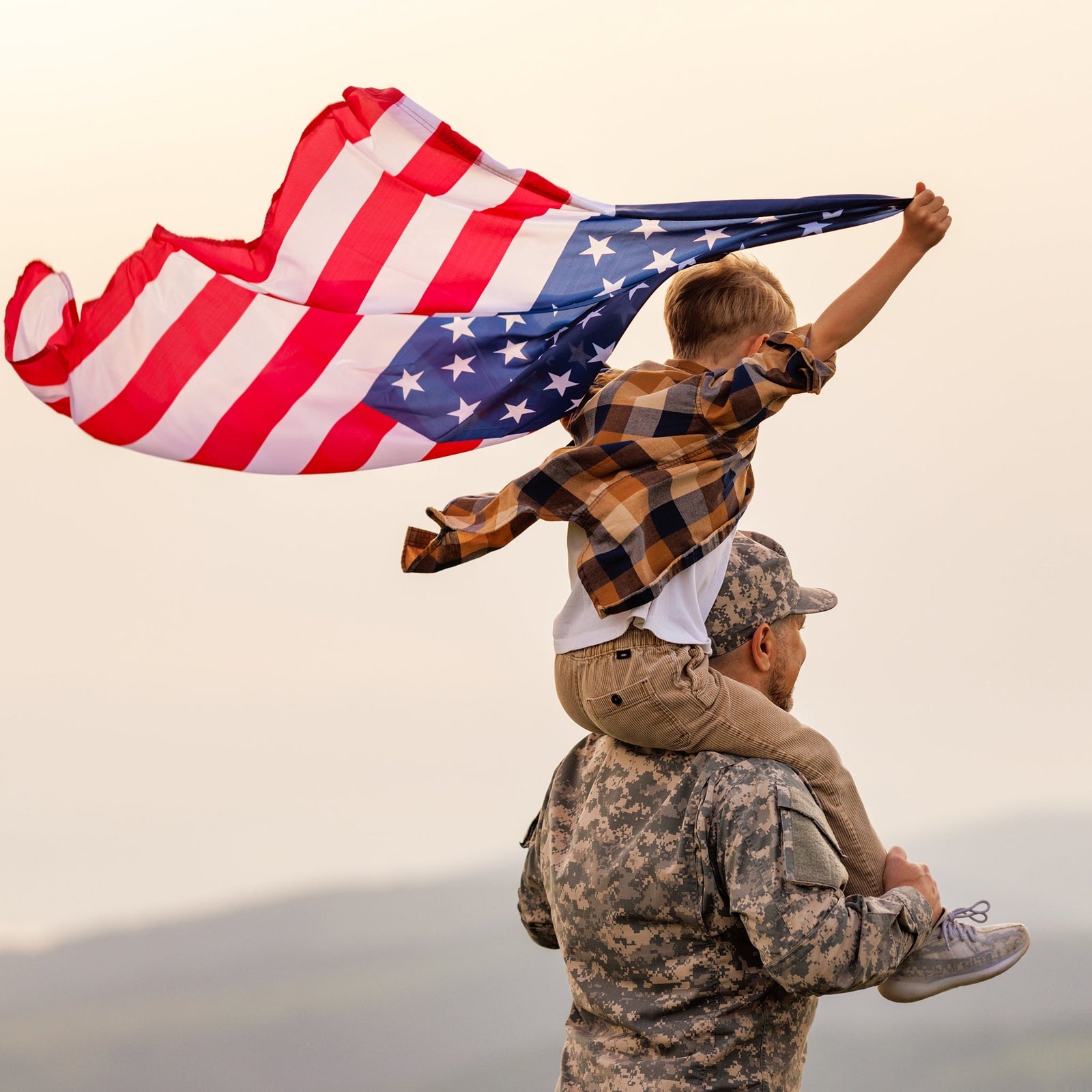 U.S. soldier lifting child with American flag during PCS send-off, representing honor, family, and new beginnings.
