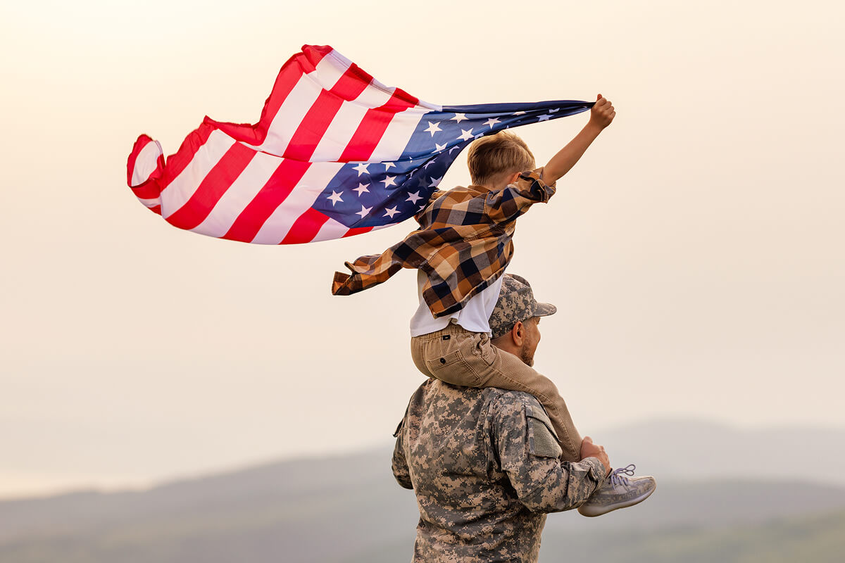 Proud veteran bonding with child under American flag—ideal visual for veteran gifts and tribute.