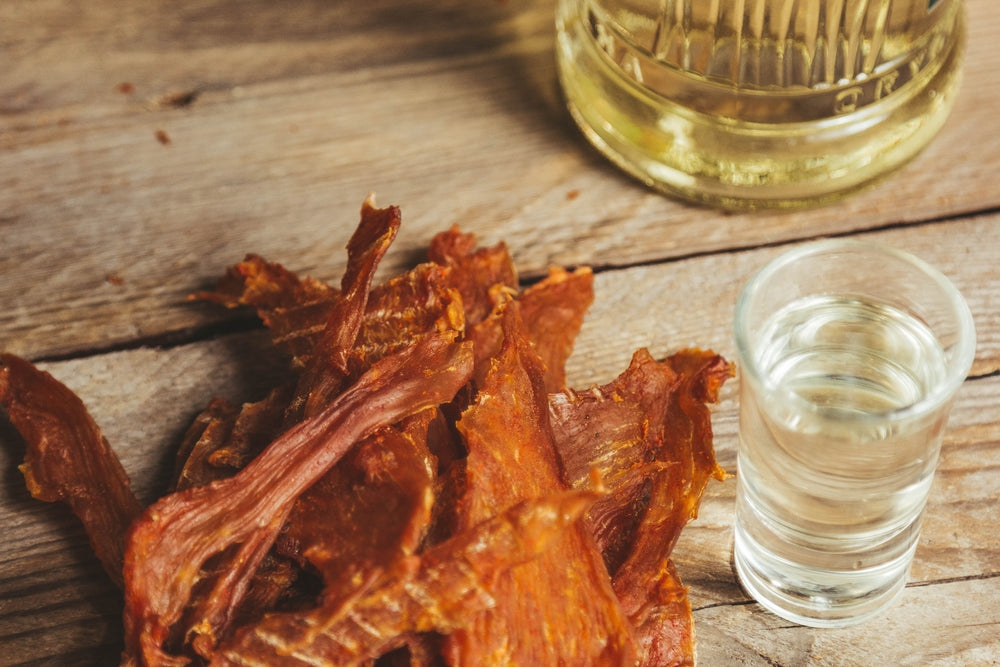 delicious jerky and Shot Glass  on a wooden background