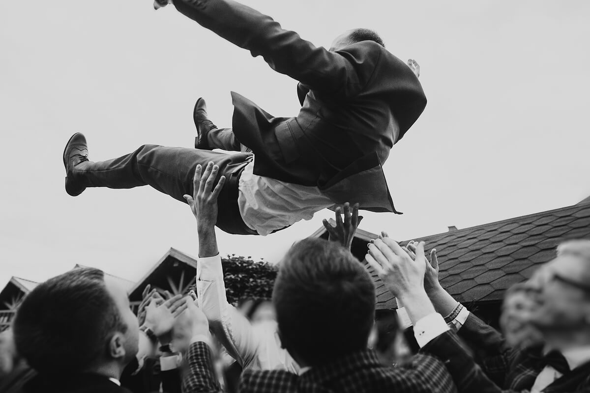 Wedding guests lifting someone up in celebration, perfect for wedding-approved favors