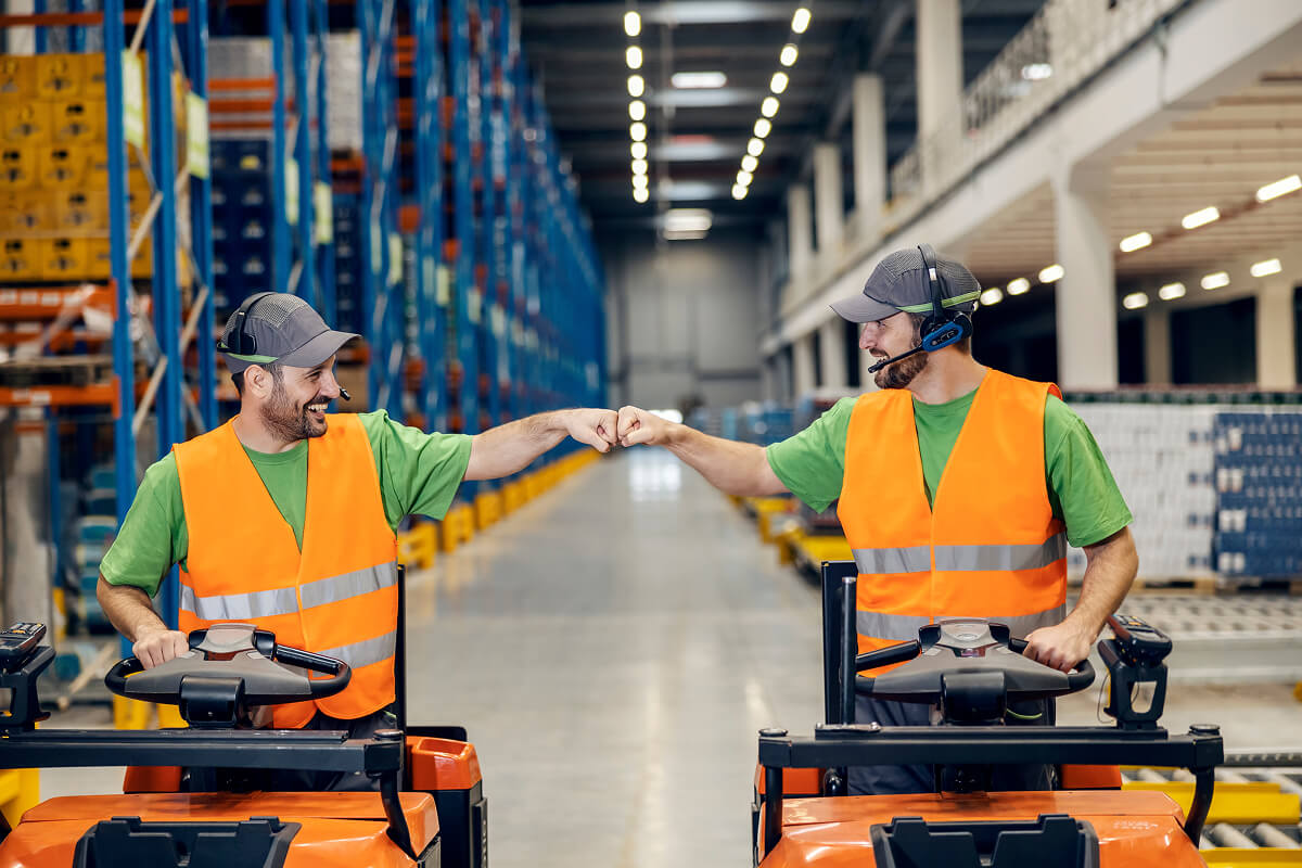 Coworkers sharing a fist bump in a warehouse—because great teamwork deserves more than just a thank-you card.