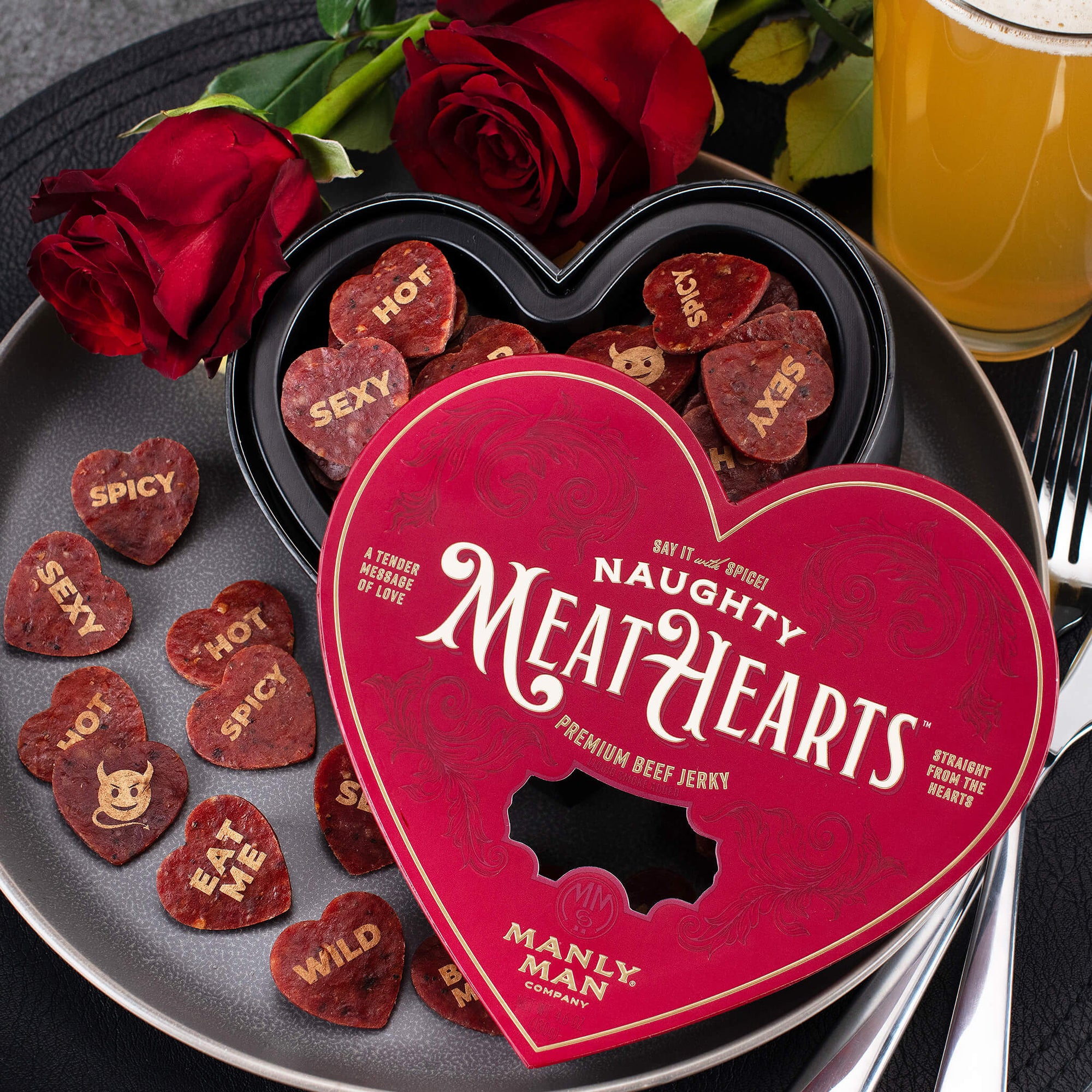 The jerky pieces are heart-shaped with fun, cheeky messages such as 'Hot,' 'Sexy,' and 'Spicy,' scattered across a rustic wooden table. The packaging and product exude humor and playfulness, perfect for a unique Valentine's Day gift.