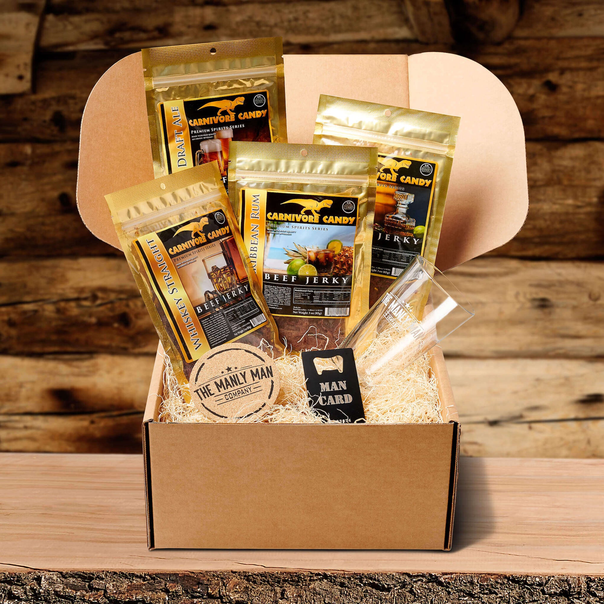 Gift crate for men, filled with alcohol-infused jerky, coaster, pint glass and man card, on log table and in front of wood panel background