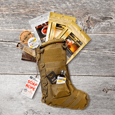 Tactical Xmas stocking kit filled with bags of jerky and male grooming gifts on gray wood panel background