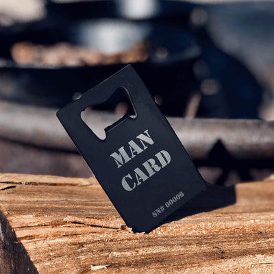 Man Card Bottle Opener standing upright on campground table