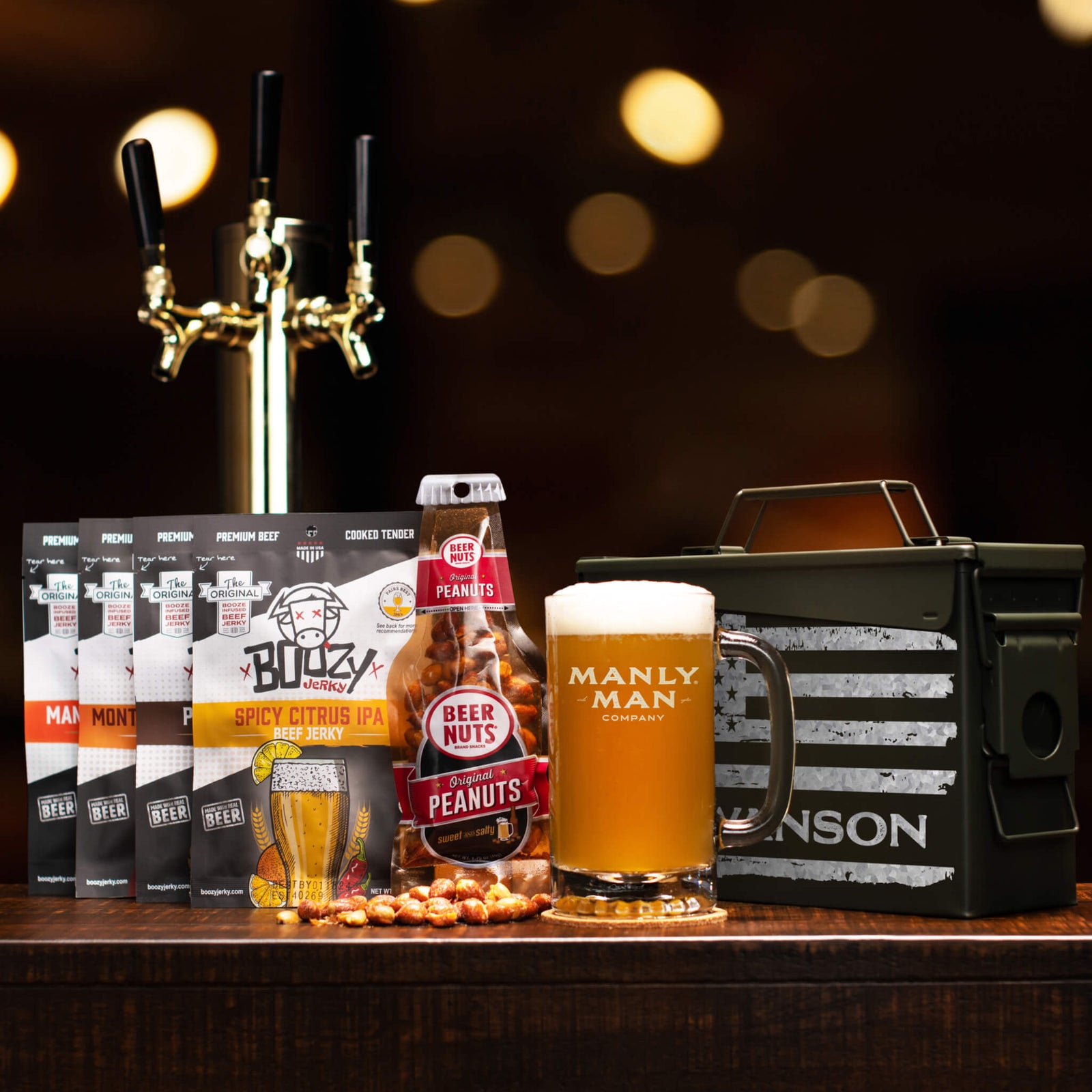 Custom ammo can gift set with jerky, peanuts, beer mug labeled 'Manly Man Company,' and tap handle in background.